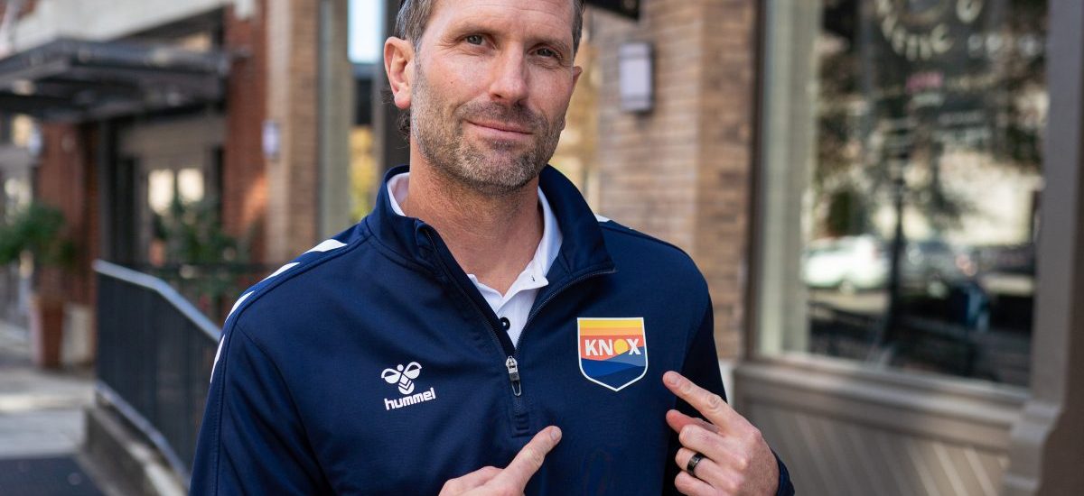 Ian Fuller pointing at the One Knox crest on his shirt